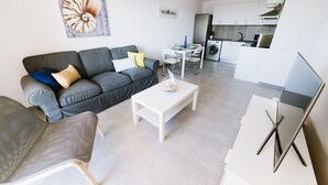 A modern living room with a grey sofa, a white coffee table, and a dining area with a table and chairs. - Ocean View apartments. Beachfront Ocean view terrace. Wifi. Parking (Gran Tarajal)
