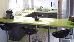 A modern kitchen with a green countertop, stainless steel appliances, and bar stools. - Apartment in El Palm-Mar, Arona, very well decorated, furnished and equipped. (Palm-Mar)
