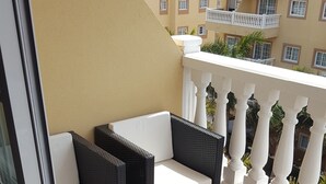 A balcony with two wicker chairs and a small table, a white balustrade, and a view of buildings in the background. - Apartment in El Palm-Mar, Arona, very well decorated, furnished and equipped. (Palm-Mar)