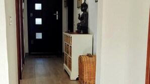 Un escalier en bois mène à une porte sombre, au-dessus de laquelle se trouve un luminaire.