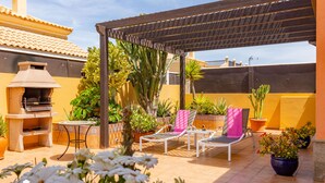 An outdoor patio with a barbecue grill, lounge chairs, and potted plants. - VILLA BELLA LUCIA 2 "heated pool, wifi, barbecue, tv satelite (Corralejo)