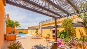 A covered outdoor area with lounge chairs, a pool, and potted plants. - VILLA BELLA LUCIA 2 "heated pool, wifi, barbecue, tv satelite (Corralejo)