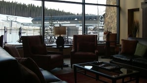 A spacious living room with large windows, a stone wall, and a view of a covered outdoor area.