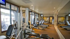 A gym with various exercise equipment, including treadmills and weight machines, arranged in rows.