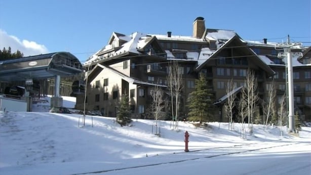 A large, multi-story hotel with a ski resort backdrop.