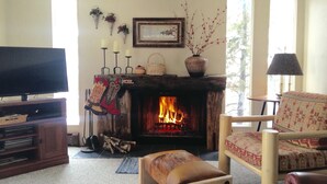 A cozy living room with a fireplace, a television, and a patterned armchair.
