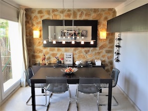 A dining area with a stone wall, a black table, and four chairs. There is a sign that says "SLOW DOWN AND RELAX" on the table.