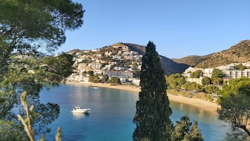 Un pueblo costero con edificios en una colina, un mar azul cristalino y un barco.