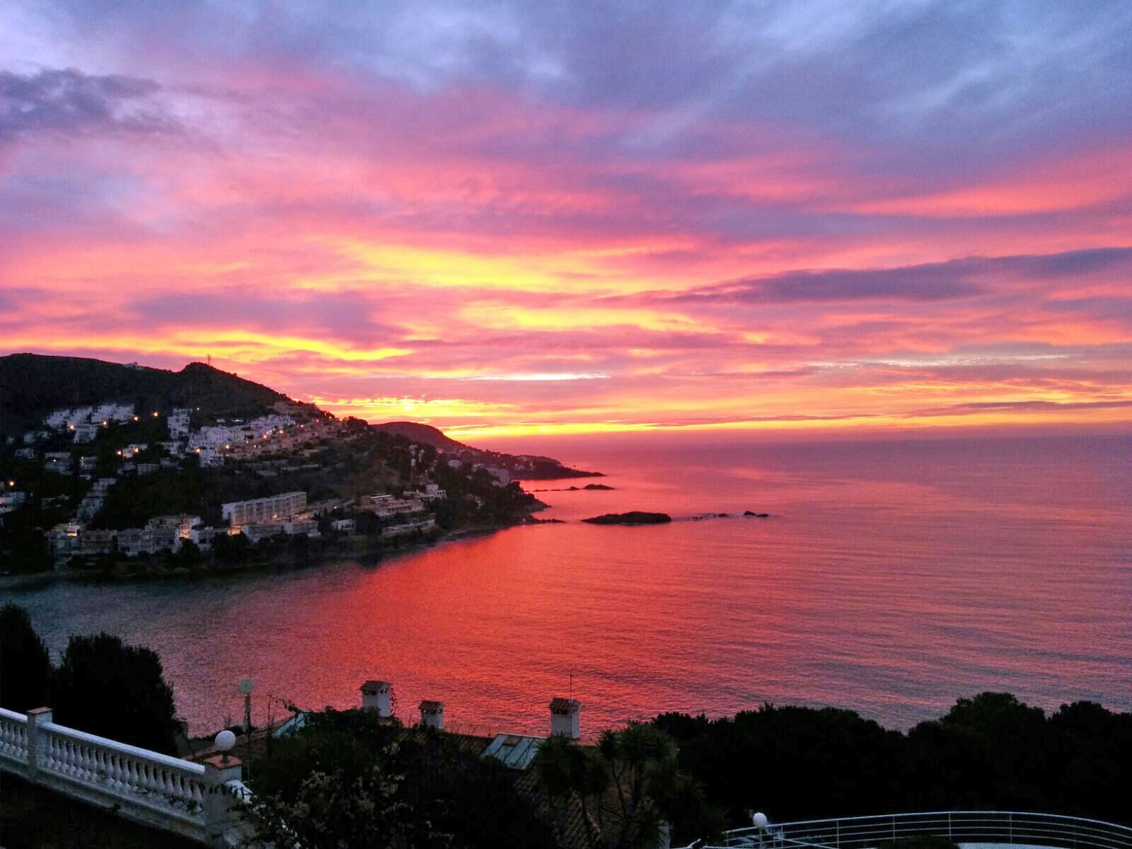 A coastal sunset view with buildings along the shoreline.