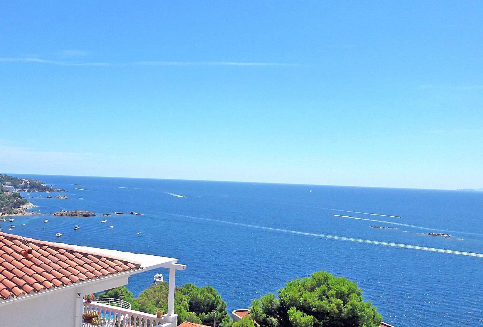 Une vue sur la côte, avec des bateaux, un ciel dégagé et un bâtiment doté d’un toit en tuiles.
