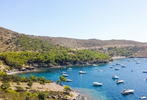 A coastal area with boats, a beach, and a building on a hillside. - Lovely seaview studio and large terrace 5m from the beach - Casa ArteVida (Roses)