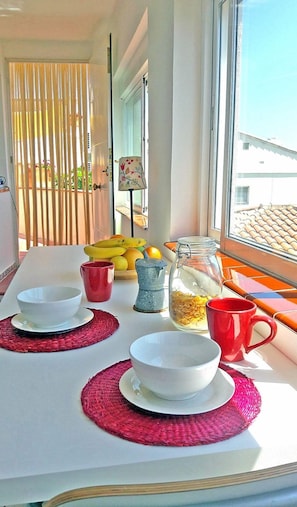 A dining table with plates, cups, and a fruit bowl.