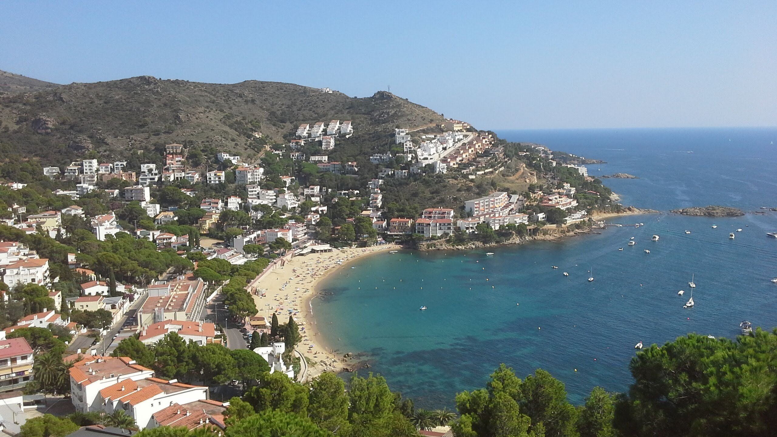 A coastal town with a beach, buildings, and boats.