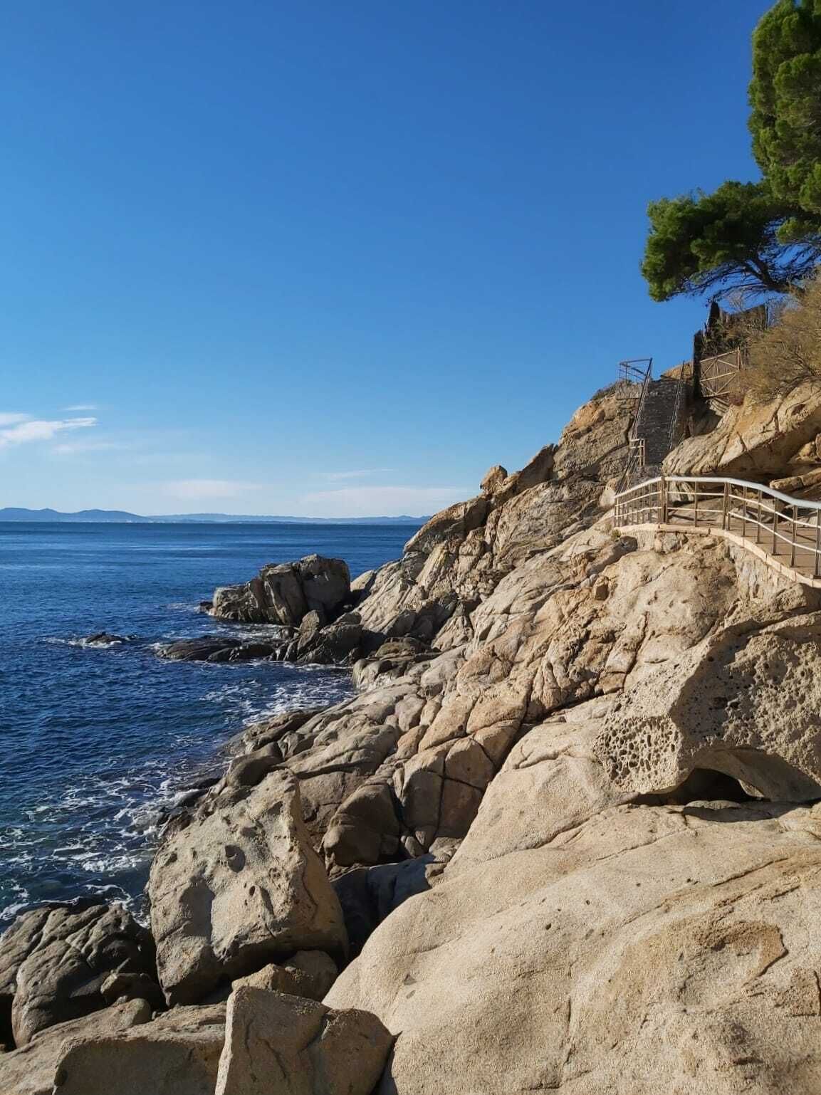 Un paisaje costero rocoso con una escalera de madera que sube hacia un acantilado.