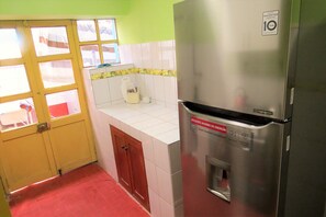 A kitchen with a stainless steel refrigerator, a yellow door, and a red floor.