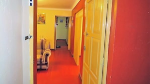 Een hal met een rood tapijt, gele deuren en een gestreept fauteuil.