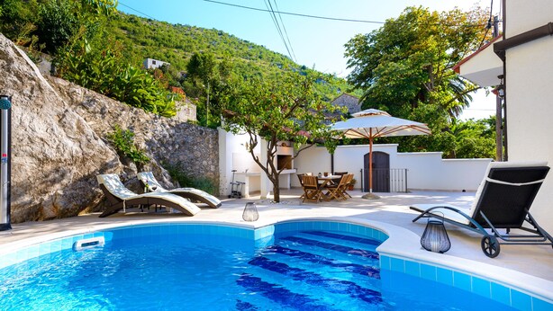 A swimming pool with lounge chairs, a table, and a lamp.