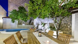 A wooden dining table with chairs, a candle centerpiece, and a pool in the background.
