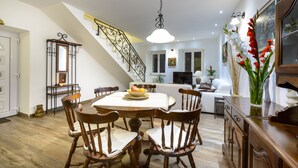 A dining area with a round table, wooden chairs, and a staircase with a wrought iron railing.