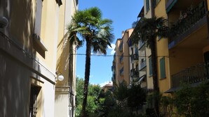A narrow alleyway with buildings on either side, featuring balconies with railings and potted plants. - THE HIDDEN GARDEN (Bologna)