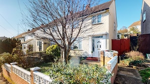 A residential house with a front garden, a red gate, and a white door.