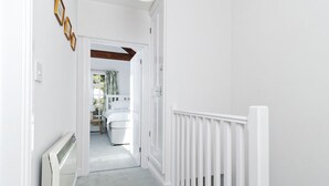 A hallway with white walls, a white radiator, and a white railing. - Cosy cottage in sleepy village yet only 5 minute drive to Truro city centre.  (Malpas)