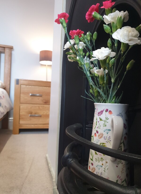 Un arreglo floral en una taza estampada sobre un soporte de metal negro.