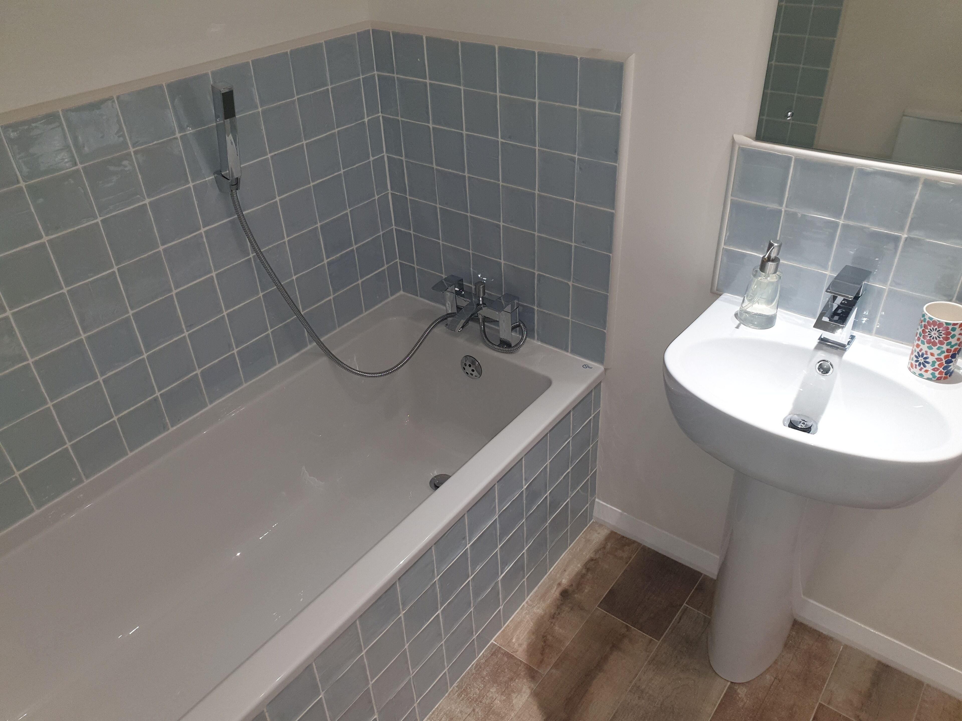 A bathroom with a bathtub, a sink, and a mirror.