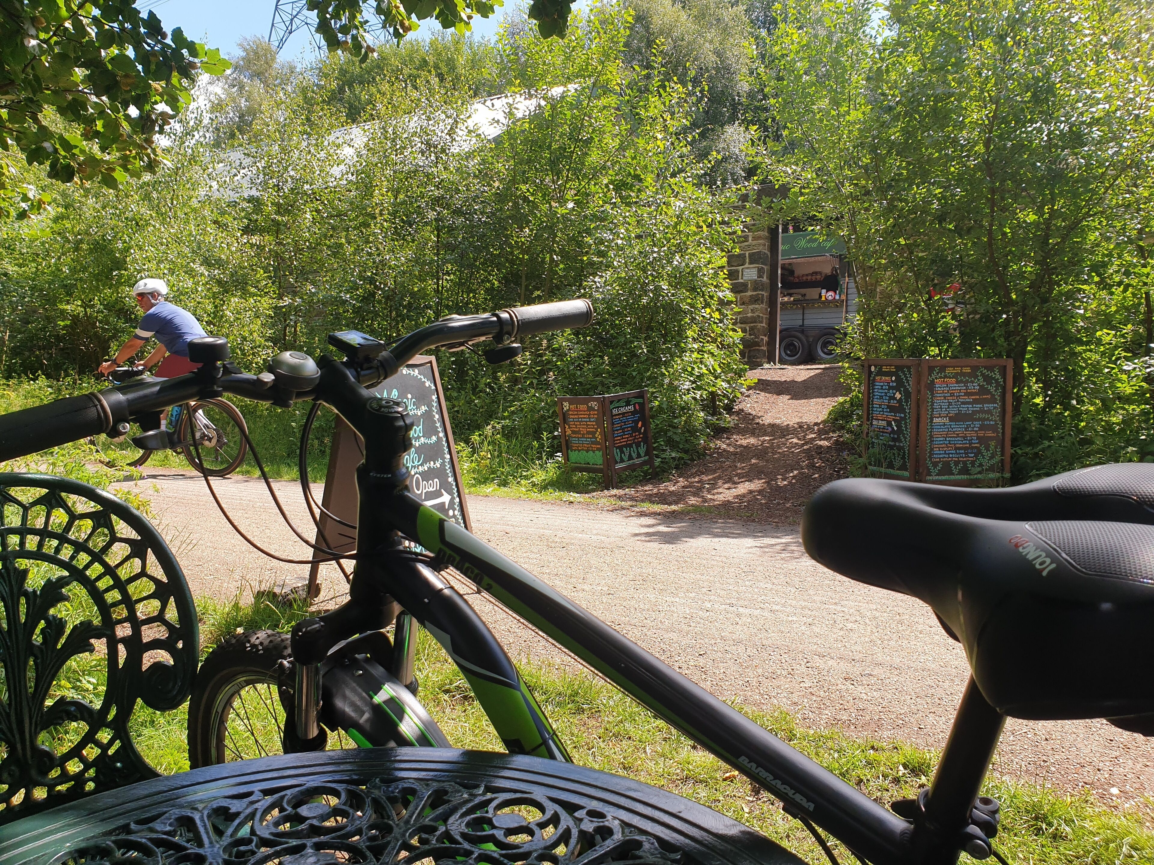 Ein Fahrrad steht in einem Park, mit einem Schild und einer Person, die im Hintergrund Fahrrad fährt.