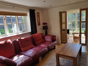 A living room with a red leather sofa, a wooden coffee table, and a large window with blinds.