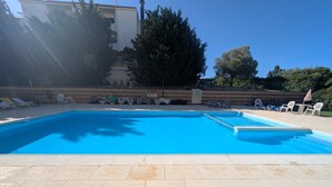 Une piscine rectangulaire à l’eau d’un bleu limpide, entourée d’un sol carrelé de couleur claire.