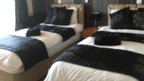 Une chambre d’hôtel avec deux lits, des lambris sombres, un tableau encadré au mur et un plancher en bois.