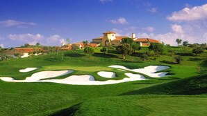 Un parcours de golf avec des bunkers et un club-house en arrière-plan.