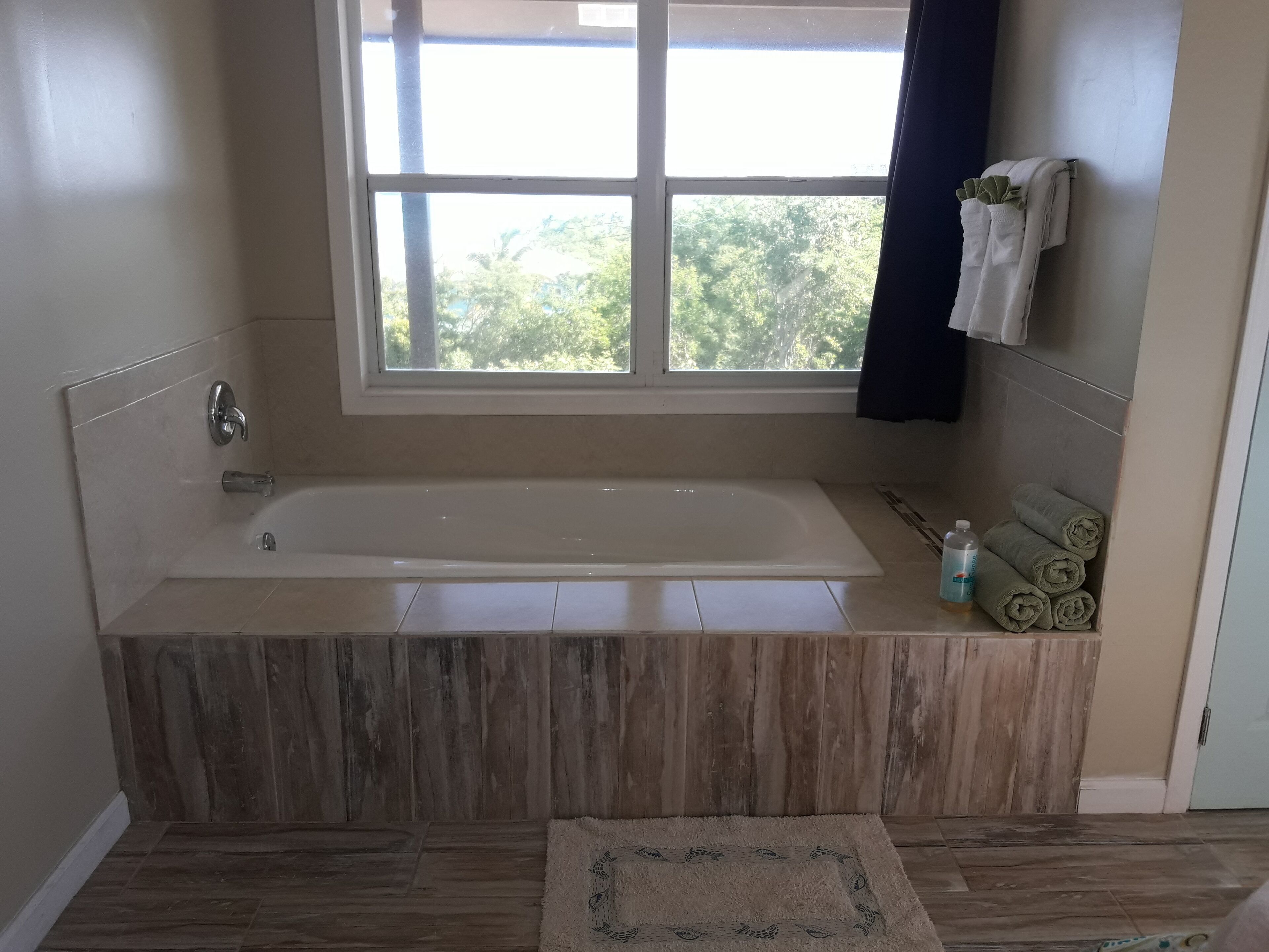 A bathroom with a bathtub, a window, and a towel rack.
