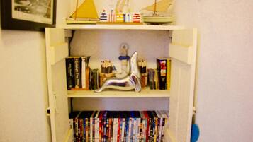 A bookshelf with various books and decorative items, including a model ship and a silver sculpture.