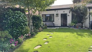 Ein gepflegter Garten mit einem Kiesweg, der zu einer Bank und einer Tür führt.