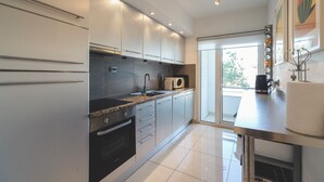 A modern kitchen with stainless steel appliances, a large window, and a view of the outdoors. - Marina Apartment | Poolside Balcony | Walk to Town & Beaches (Lagos)