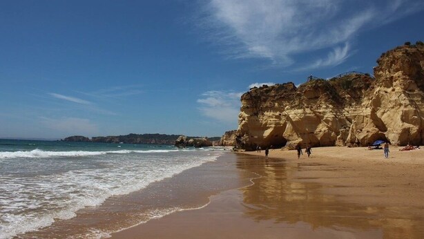 A beach with clear skies, rocky cliffs, and calm waves. - Marina Apartment | Poolside Balcony | Walk to Town & Beaches (Lagos)
