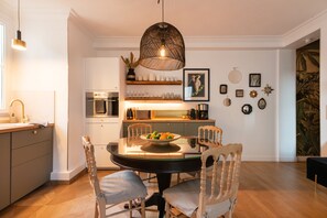 Een moderne keuken met een eethoek, met een ronde tafel, stoelen en een hanglamp.
