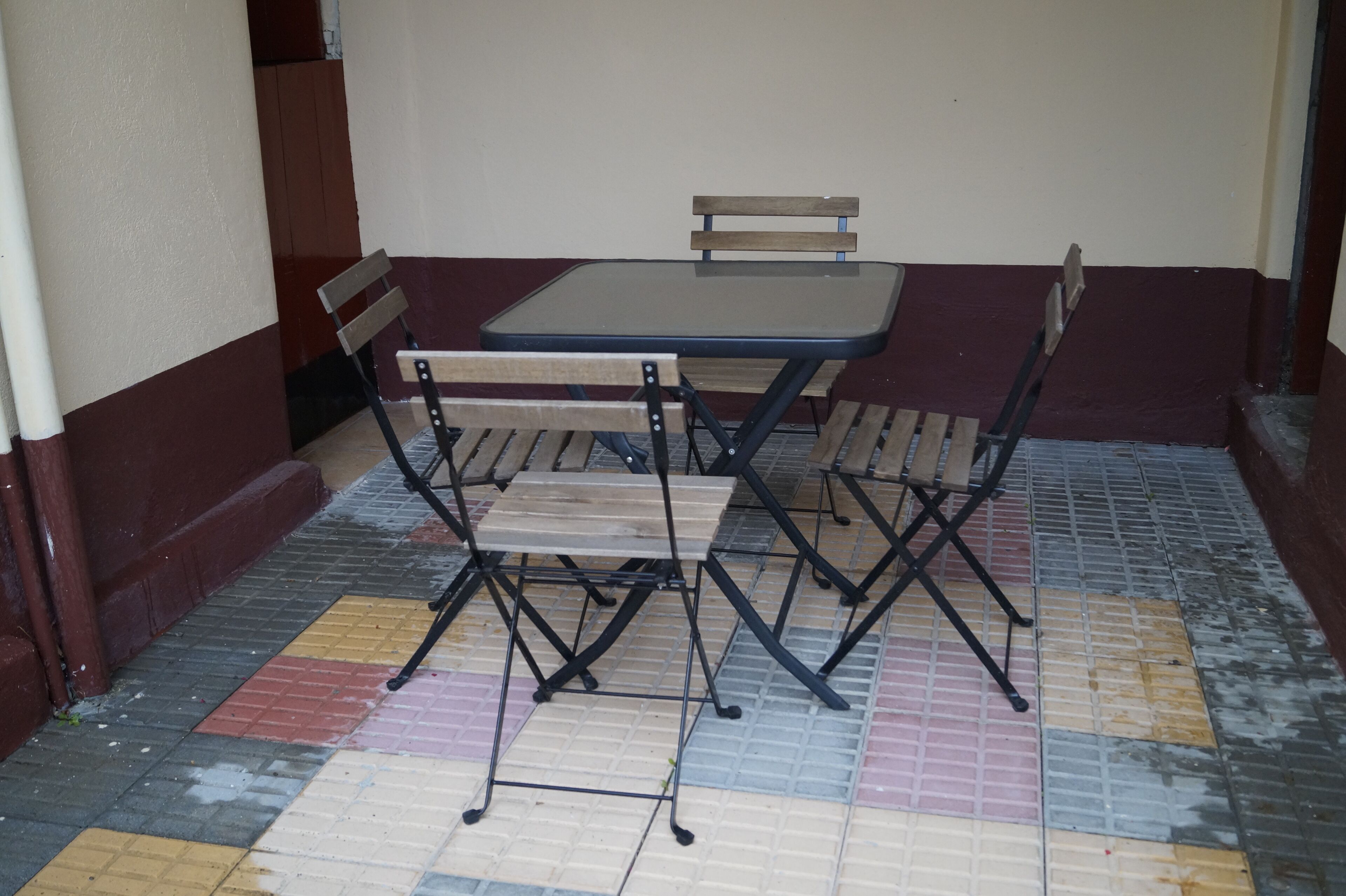 Un petit espace extérieur aménagé pour prendre les repas, avec une table et quatre chaises.