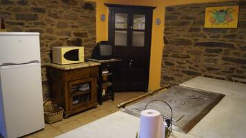 Une cuisine avec un mur en pierre, un four à micro-ondes, une cuisinière et un réfrigérateur.