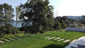 Un área con césped y un sendero de piedra que lleva a un edificio blanco.