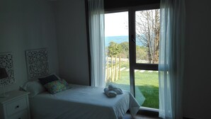 Un dormitorio con cama, mesita de noche y ventana con vista al exterior.