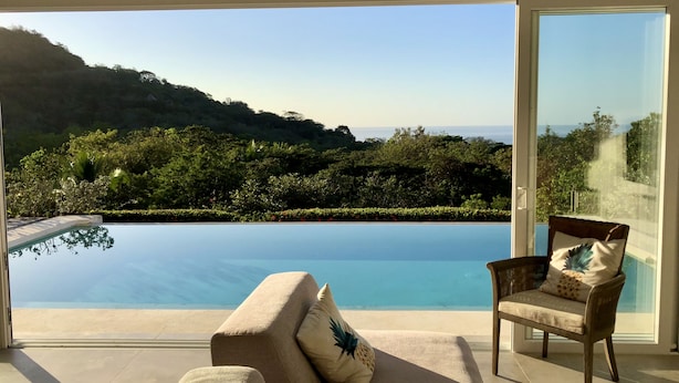 A room with a large glass door leading to a pool and a view of the sea. - Private Ocean-View Family Villa with Pool in Islita, Costa Rica (Islita)
