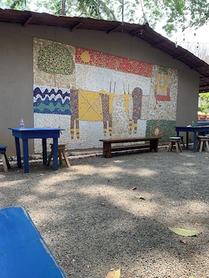 Pared de mosaicos con un banco y mesas en una zona de estar al aire libre.