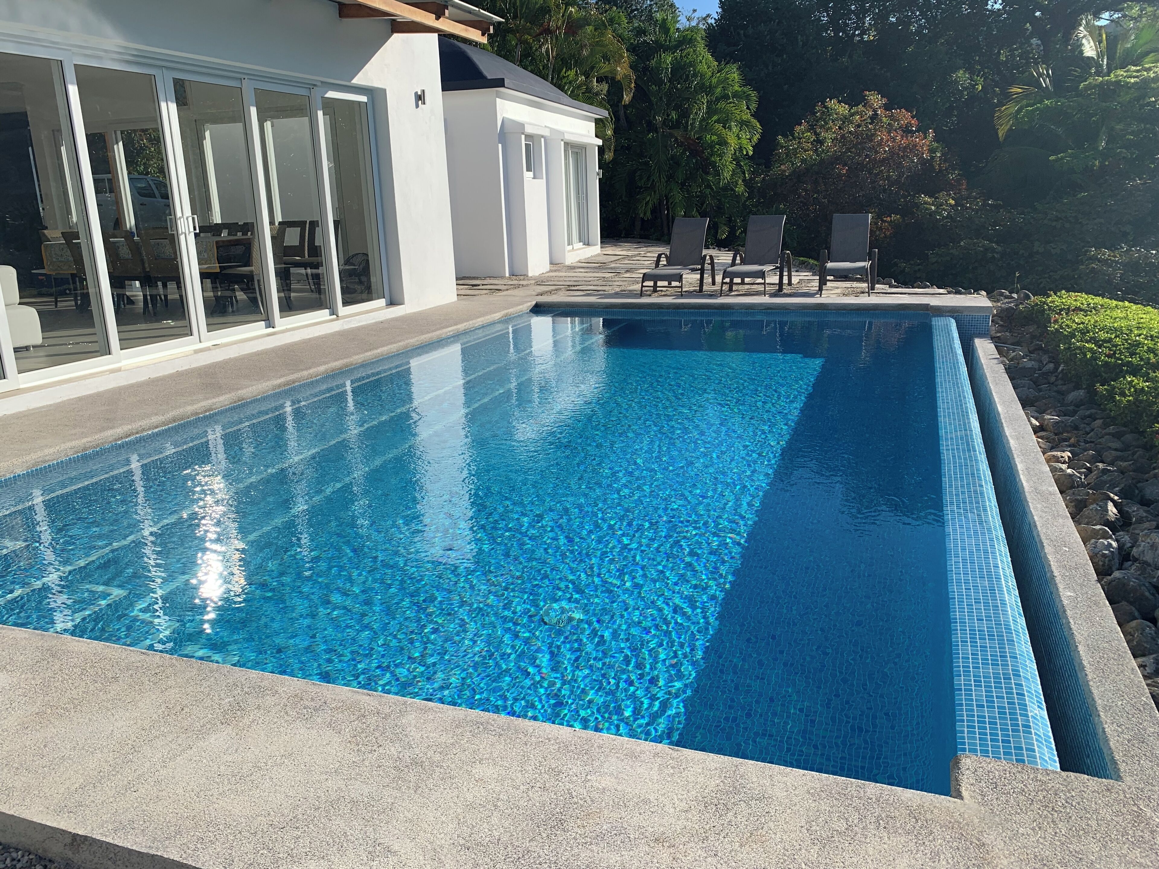 Ein rechteckiger Pool mit klarem, blauem Wasser, umgeben von einer Steindeck.