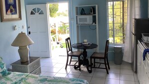 A compact kitchen with a dining table, chairs, a microwave, and an air conditioning unit. - Garden Delight Studio is conveniently located in Rodney Bay! (Rodney Bay)