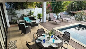 A covered outdoor area with a pool, seating, and potted plants.
