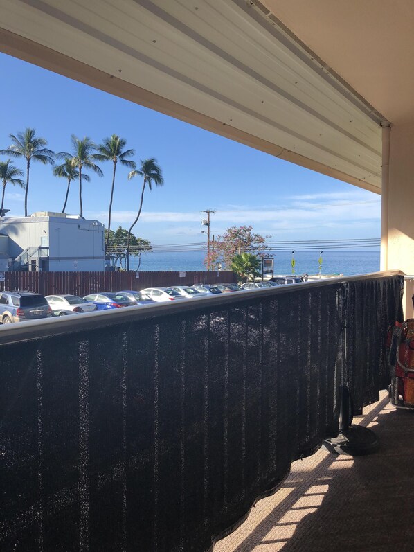 Un balcón con vistas a un estacionamiento, palmeras y un edificio al otro lado de la calle.