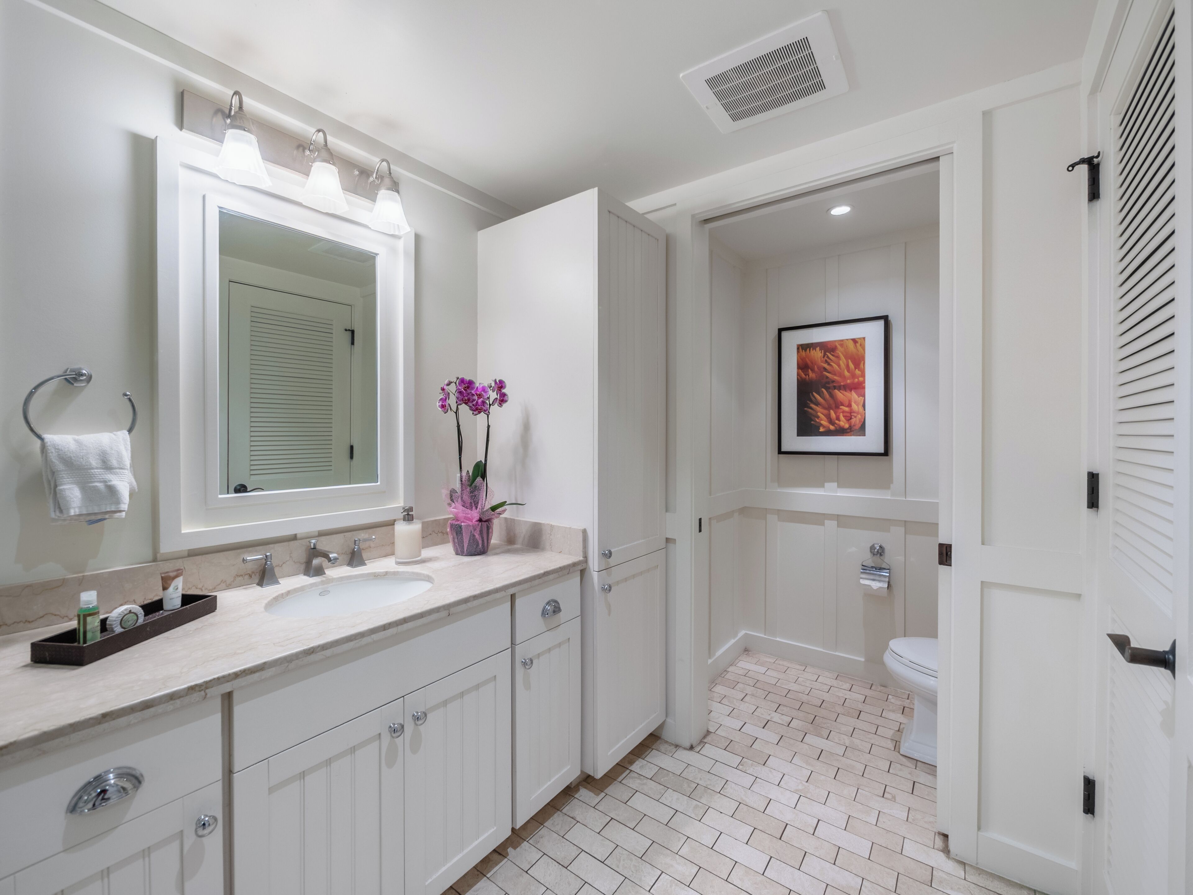 A modern bathroom with a large mirror, dual sinks, a toilet, and a shower area.